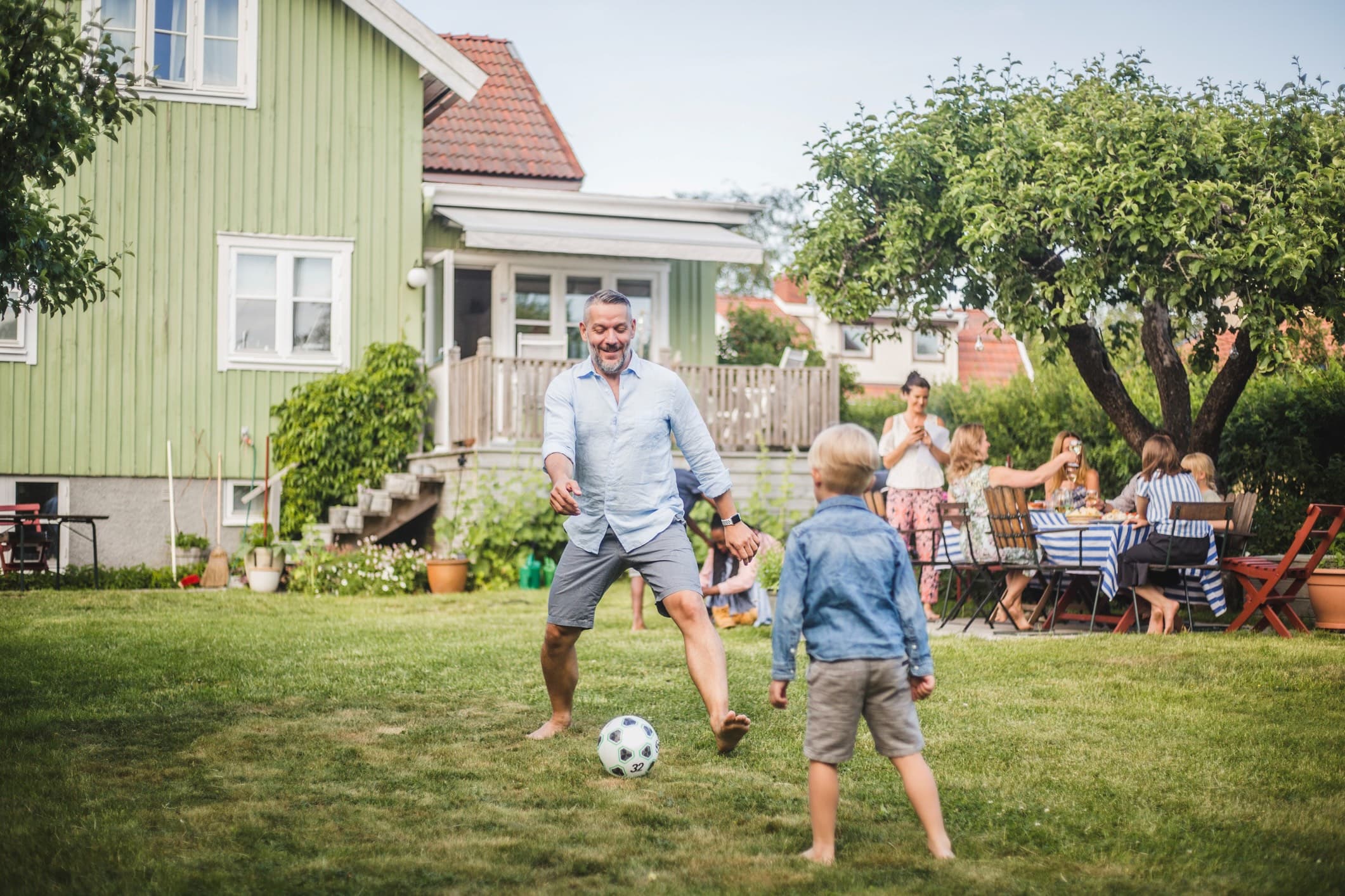 En pappa spelar fotboll med sin son i trädgården