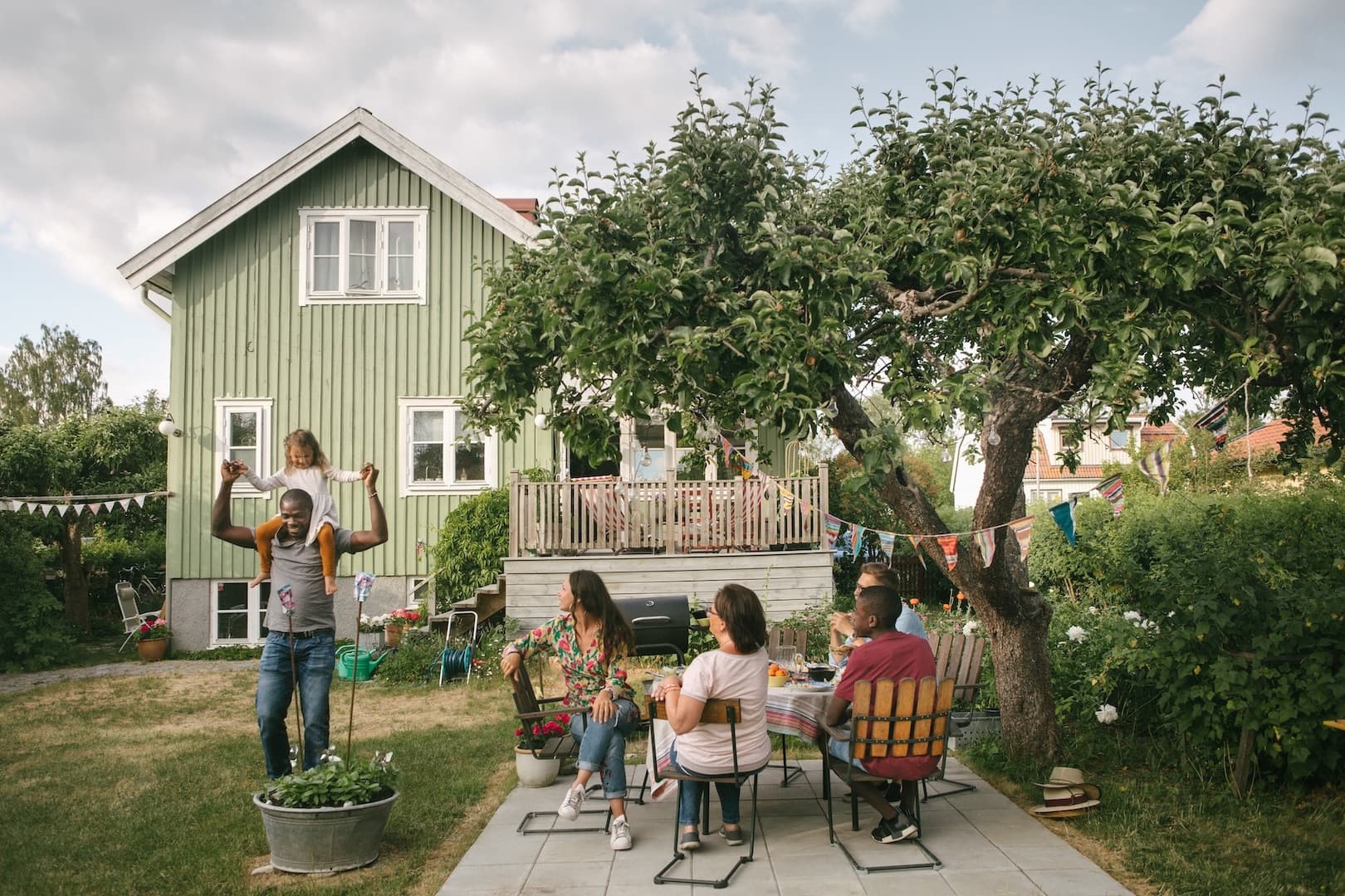 En pappa bär sin dotter på sina axlar i trädgården