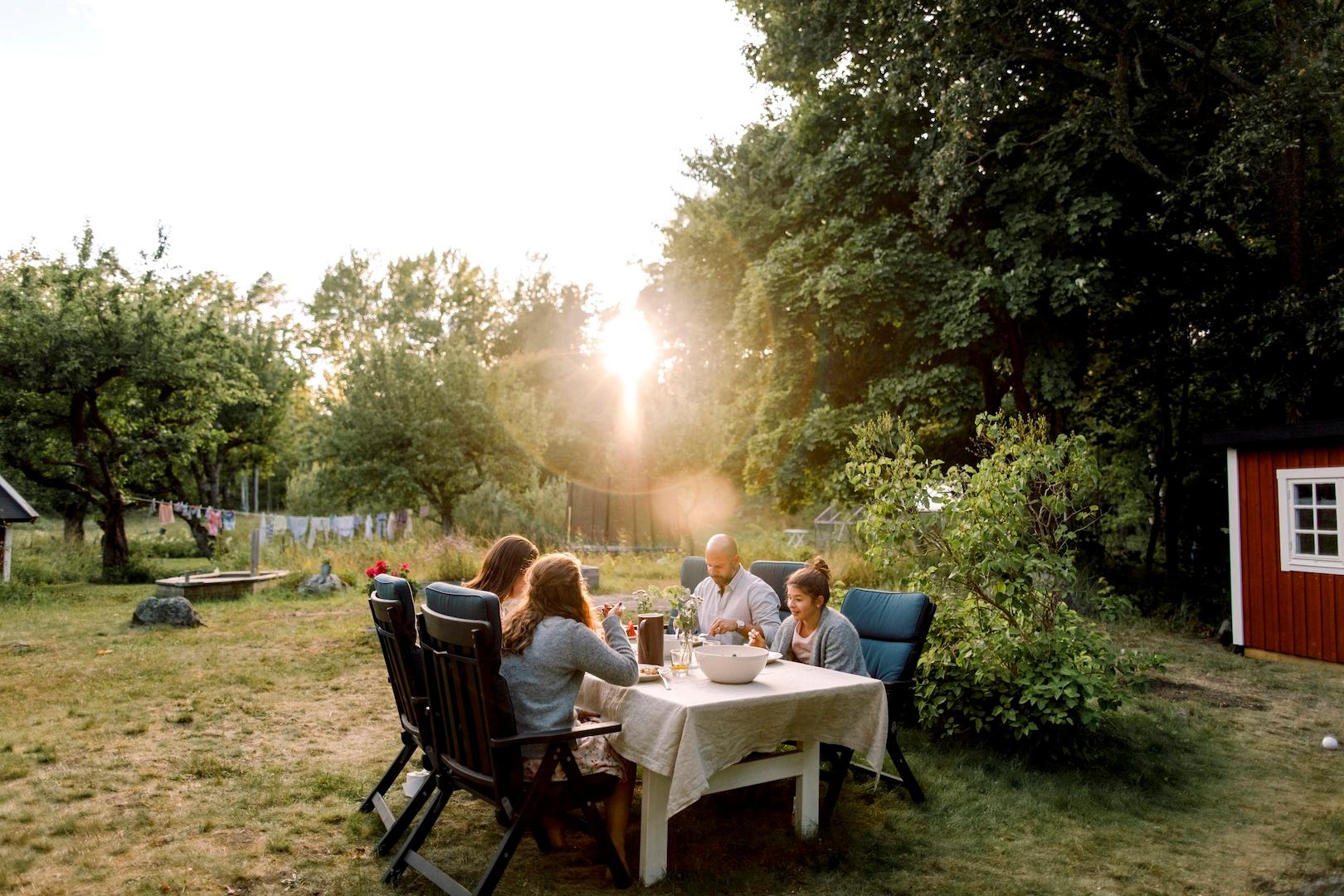 En familj äter middag i solnedgången i trädgården